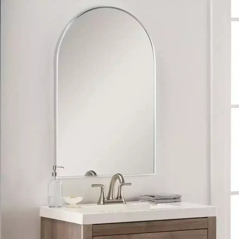 Miroir de salle de bain mural arqué à cadre métallique noir.